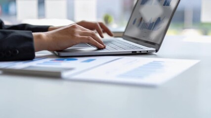 明るいオフィスで女性がノートパソコンの画面に表示されたデータグラフを見ながらキーボードを操作している様子 - Powered by Adobe