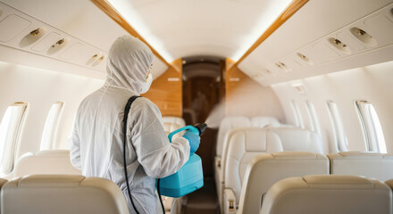 Disinfecting private jet interior with protective gear