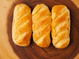 Three French soft and golden brioche rolls on wooden background. Premium top quality pastry product. Fine and delicate dessert.