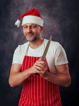 Male butcher or fish monger in white shirt, red and white classic apron and red Santa hat. Friendly looking professional dressed for special festive season. model in his 50s with grey beard.