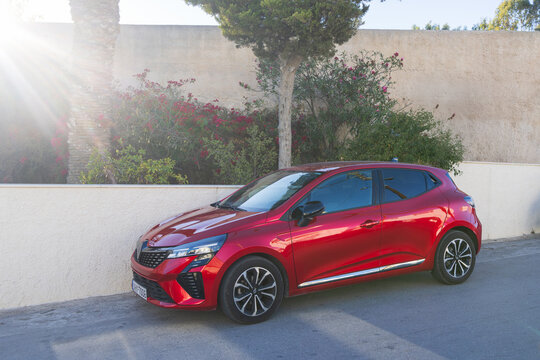 Red Renault Clio hatchback car parked on a sunny street in Santorini, Greece, 5 October 2025
