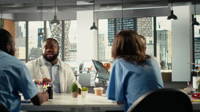 Diverse physicians team reviewing clinical records and working together to share expertise and diagnostic results to improve healthcare services at the hospital. Brainstorm treatment ideas. Camera B.