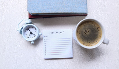 To do list sheet on desk surrounded by books, glasses, clock, coffee. Checklist of tasks to complete. Business planning, design and reminder. To do list and list of numbers on a table.