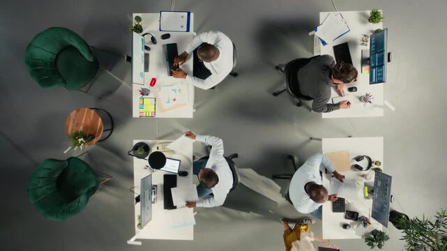 Top down view of colleagues exchanging ideas during business meeting. Professional team examining financial data, targets and business intel to align goals for company progress. Camera A.