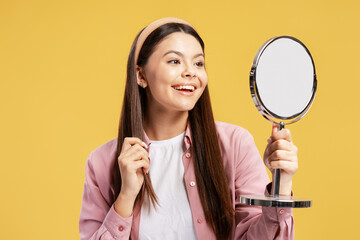 Young woman smiling, admiring reflection in mirror, feeling happy with self care