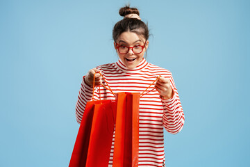 Excited woman opening shopping bags discovering a surprise or gift from a purchase