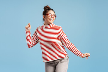 Happy young woman dancing with joy and positive energy on a blue background
