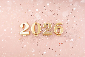 2026 golden candles with glitter and confetti on pink pastel background top view flat lay New Year copy space