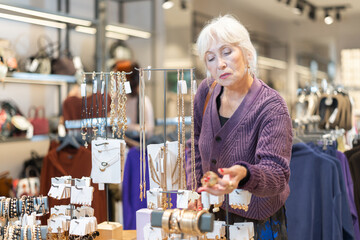 Customer inspect at products in store and pick out accessories. Senior woman search and choose bracelet. Market conjuncture, ratio of supply and demand