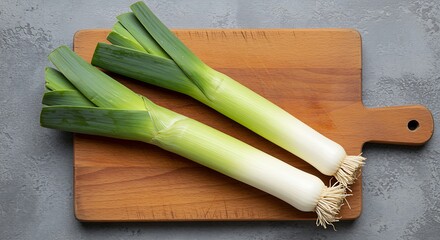 Two fresh leeks with green tops on a wooden cutting board vegetable white