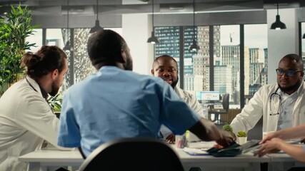 Diverse surgeons staff in a clinic discussing therapy options and research analysis. The meeting highlights professionalism and innovation in healthcare planning in hospital. Camera B. - Powered by Adobe