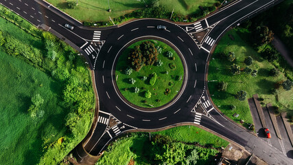 Aerial view of a circular traffic roundabout surrounded by lush greenery and landscaped gardens,...