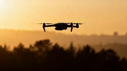 Drone silhouette flying over a hazy forest landscape during golden orange sunset. Ideal for themes of technology, outdoor exploration, or aerial photography, suitable for promotional materials