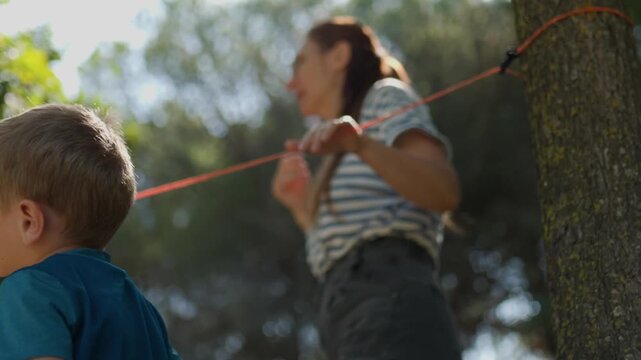 Mother and son setting up slackline in a sunny park