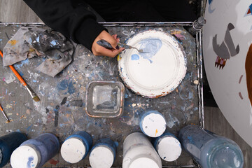 Artist mixing white and blue paint on a messy palette