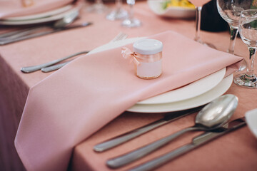 Pink table setting with party favor jar on napkin