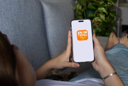 Rosario, Argentine. November,18,2025:Calm woman holding a smartphone displaying an online retail application, shopping from home with mobile technology for convenient Christmas purchase