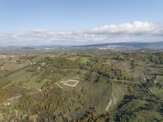 Aerial view of rolling hills painted with autumn's touch, where vineyards meet forests under a vast sky, Lapio, Irpinia, Campania, Italy.