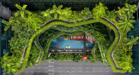 Aerial view of lush greenery cascades over the hotel's terraced balconies and pool, contrasting with the grey city street below, Singapore, Central Singapore Community Deve, Singapore.