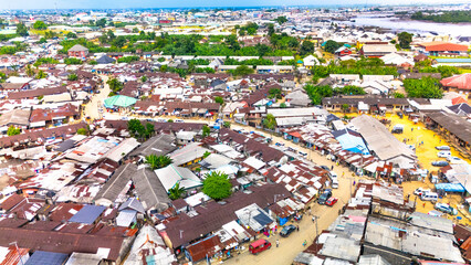 Aerial view of rooftops and roads interweave amidst lush greenery, capturing the vibrant life of Bundu Waterfront, Port Harcourt, Rivers, Nigeria.