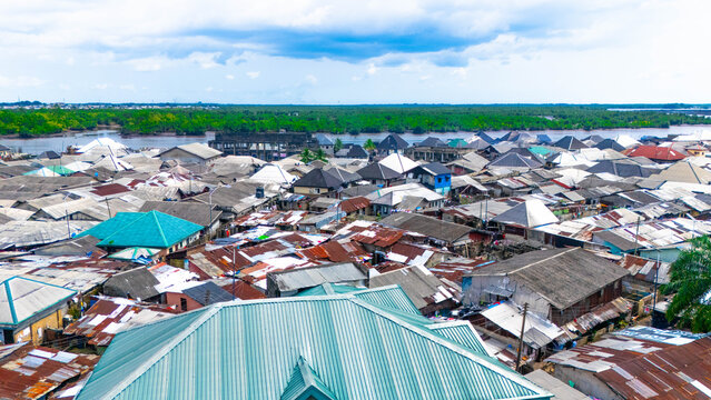 Aerial view of rooftops sprawling like a colourful patchwork quilt, blending with the waterfront's edge, under a vast sky, Bundu Waterfront, Port Harcourt, Rivers, Nigeria.