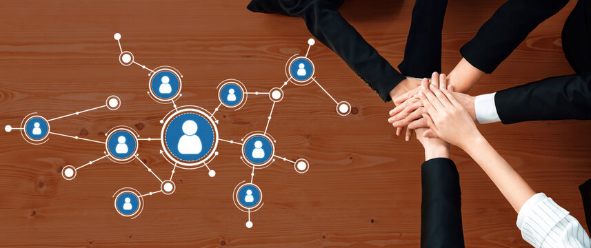 Hands unite on a wooden table with an overlaid graphic of human connections, symbolizing teamwork in a business environment focused on collaboration and networking. Amity - Powered by Adobe
