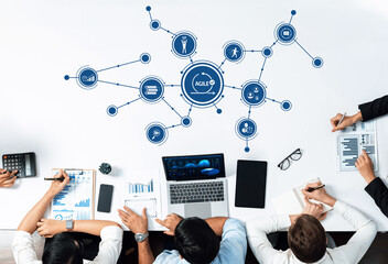 A modern business meeting showing professionals collaborating over laptops and charts in an agile workspace. The session focuses on strategy and data visualization concepts. Amity