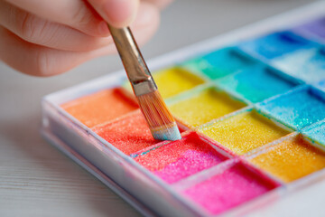 Child paints with vibrant watercolors during an art activity at home on a sunny afternoon