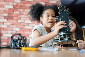 Young Girl Learning Robotics and Programming in a STEM Education Class, Students Examining a Robotic Arm Prototype, African American Child Engaged in Hands-on Tech Project with Teacher Guidance