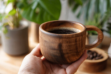 Enjoying aromatic coffee in a wooden cup surrounded by greenery in a cozy kitchen