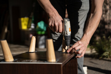 Man Assembling Furniture With Power Drill in Outdoor Space