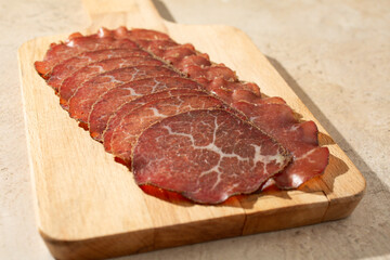 A view of bresaola slices, on a wood board.