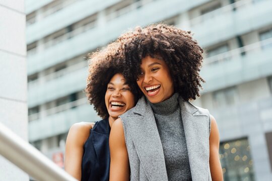 Stylish Women Laughing in Urban Setting