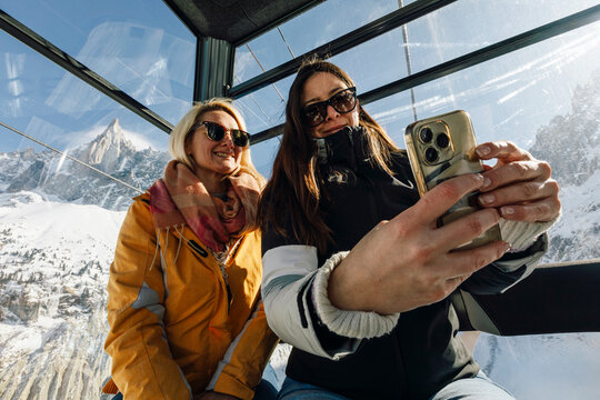 Sisters Riding Cable Car Over Snowy Alps