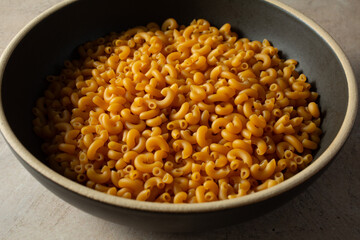 A view of a pile of dry gluten-free elbow pasta, in a bowl.