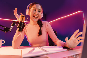 Smiling creative young beautiful Asian influencer talking in channel with positive podcast speech...