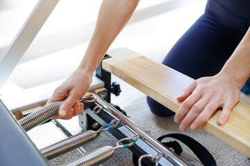 Cropped of female trainer unhook pilates reformer equipment in gym