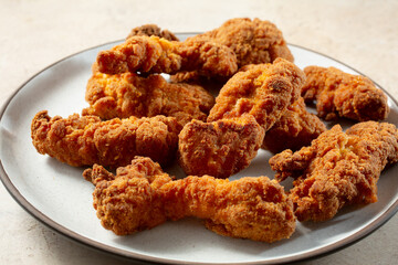 A view of a pile of gluten-free spicy chicken tenders, on a plate.