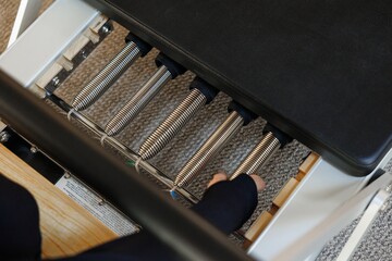 Partial top view of trainer unhook pilates reformer in fitness studio