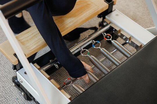 Partial of female trainer unhook pilates reformer equipment in gym