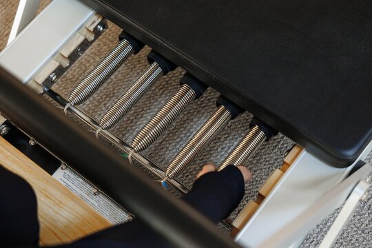 Partial top view of trainer unhook pilates reformer in fitness studio