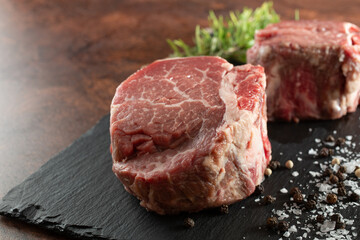 A view of some raw filet mignon on a slate board.