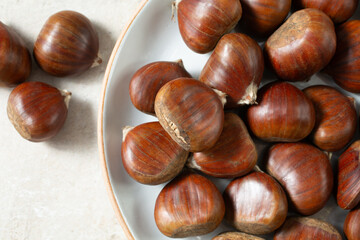 A top down view of a layer of chestnuts, on a plate.