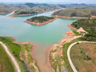 Vista do alto a seca da represa cercada de vegeta&ccedil;&atilde;o e natureza com cores vibrantes.