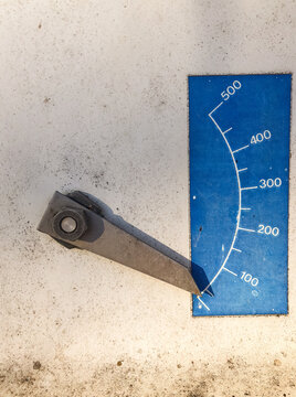 Close-up of industrial gauge needle on weathered surface