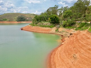 Vista do alto a seca da represa cercada de vegeta&ccedil;&atilde;o e natureza com cores vibrantes.