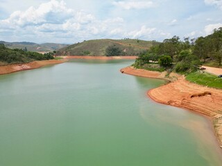 Vista do alto a seca da represa cercada de vegeta&ccedil;&atilde;o e natureza com cores vibrantes.