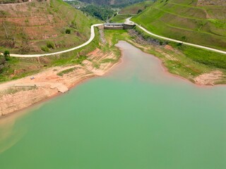 Vista do alto a seca da represa cercada de vegeta&ccedil;&atilde;o e natureza com cores vibrantes.