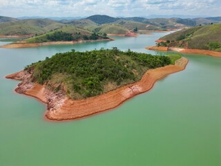 Vista do alto a seca da represa cercada de vegeta&ccedil;&atilde;o e natureza com cores vibrantes.