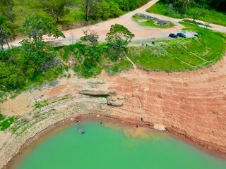 Vista do alto a seca da represa cercada de vegeta&ccedil;&atilde;o e natureza com cores vibrantes.